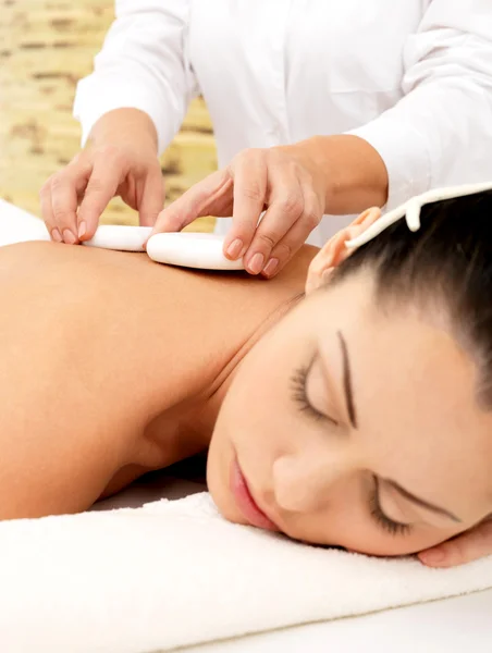 Woman having hot stone massage of body in spa salon