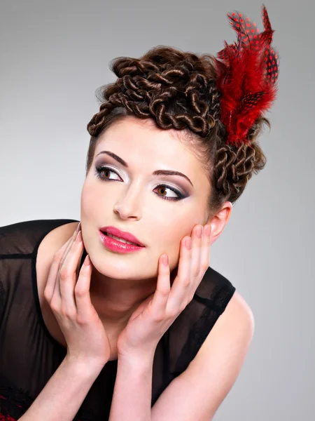 Woman with fashion hairstyle with red feather in hairs