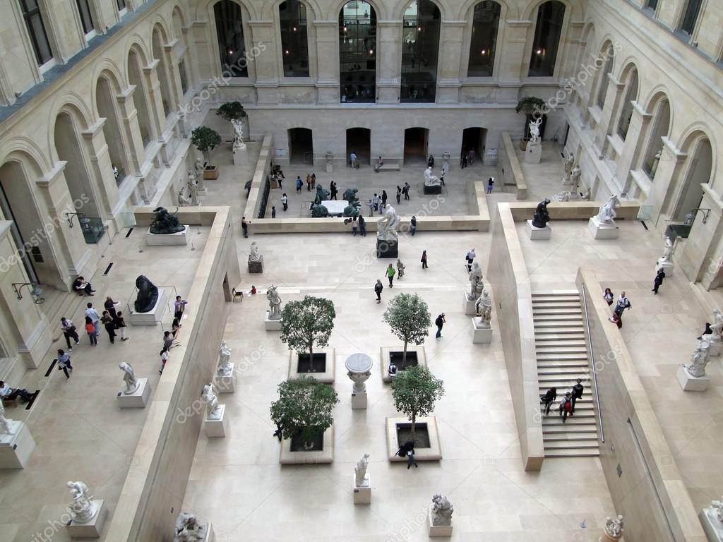Tourists explore a sculpture garden of the Louvre Museum Stock