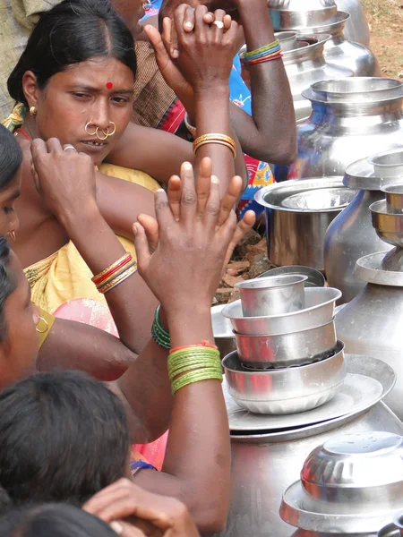 Tribal women sell home brewed liquor from large metal pots