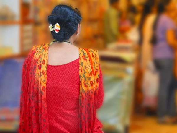 Indian woman in colorful sari browses the market stores