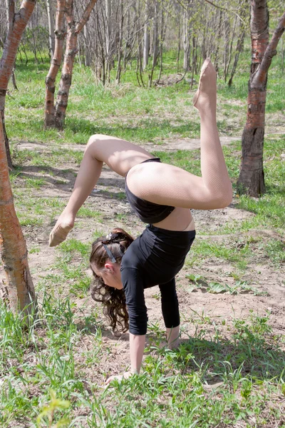 A young woman engages in a gymnastics in a summer park