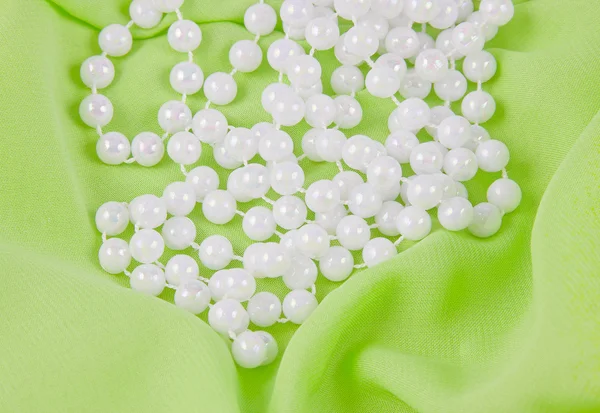 Beads from white pearls on green fabric
