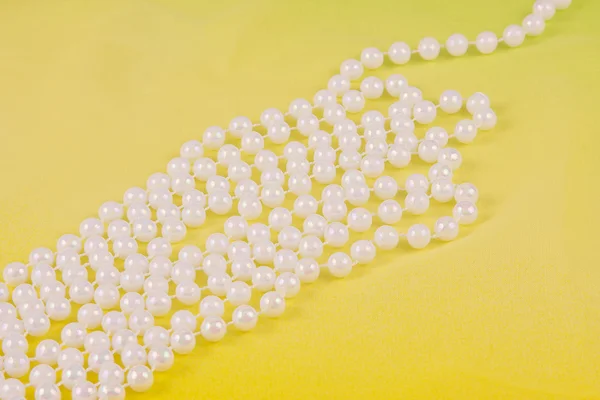 Beads from white pearls on yellow fabric