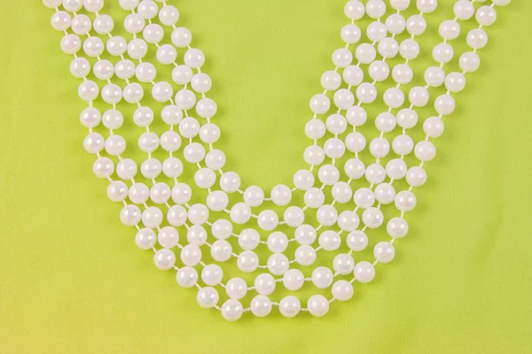 Beads from white pearls on green fabric