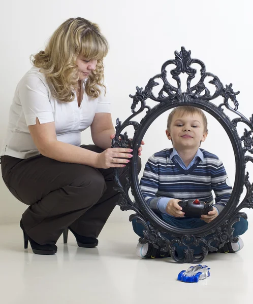 Kid play with toy car. Mom hold a frame