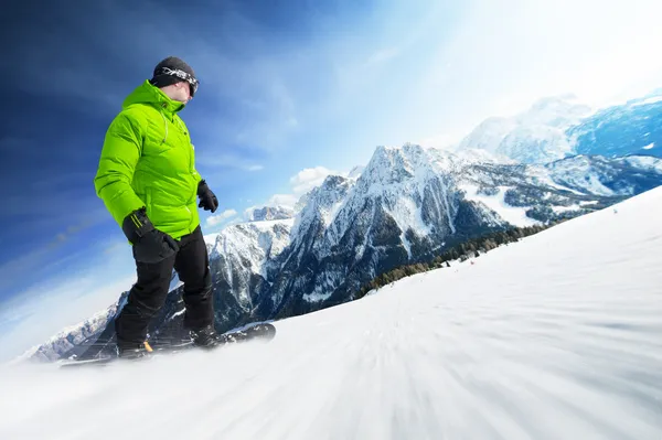 Snowboarder on piste in high mountains