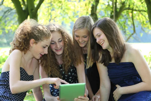 Group of four attractive young teenager working with tablet-pc