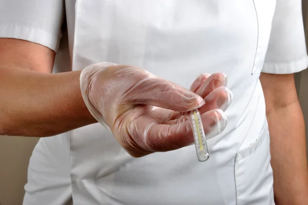 Medical staff with disposable gloves gives analogue clinical thermometer