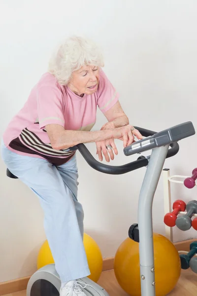 Tired Senior Woman Exercising On Bike