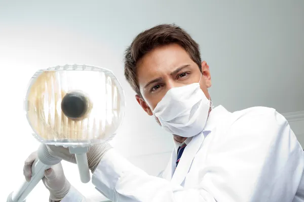 Dentist Holding Dental Lamp