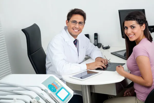 Happy Dentist And Patient At Office Desk