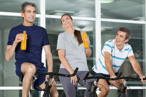 Man Looking At Friends With Juice Bottles On Spinning Bike