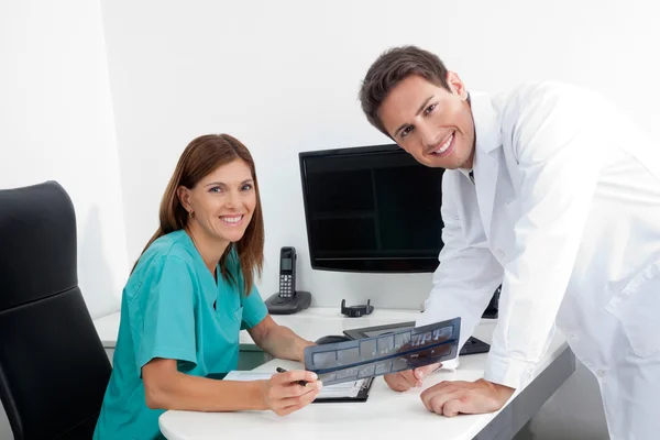 Happy Dentist And Assistant With X-Ray Report