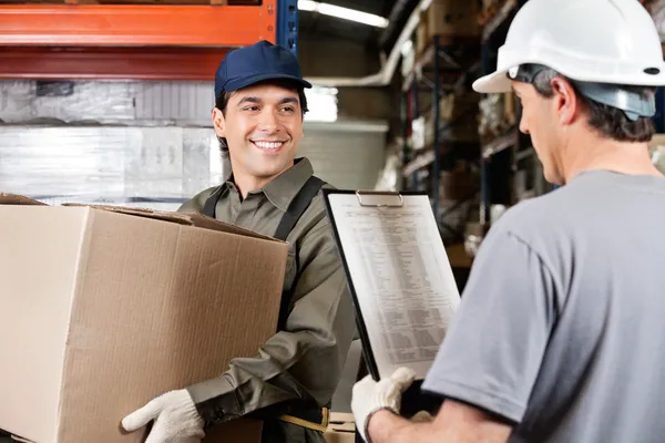 Warehouse Worker Looking At Supervisor With Clipboard