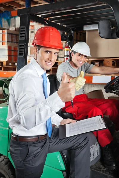 Supervisor And Forklift Driver Gesturing Thumbs Up