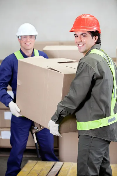 Foremen Lifting Cardboard Box in Warehouse