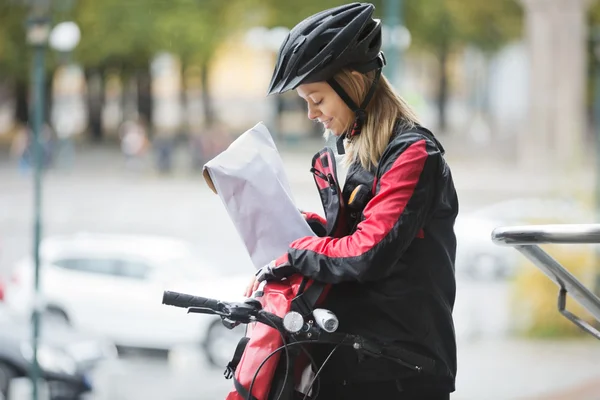 Female Cyclist Putting Package In Courier Bag