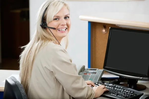 Cheerful Woman Using Computer At Reception Desk