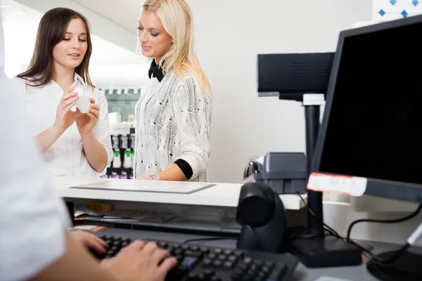 Sales Clerk Assisting Woman In Pharmacy