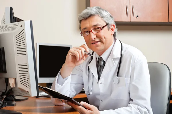 Doctor Sitting At Desk In Front Of Computer