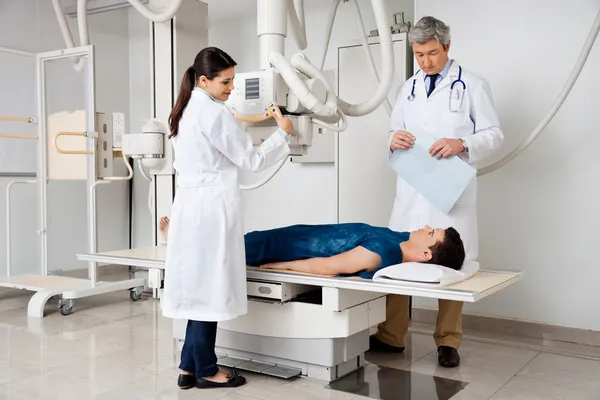 Radiologists With Patient In X-ray Room