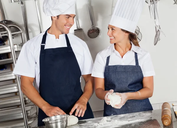 Happy Chefs Kneading Dough In Kitchen