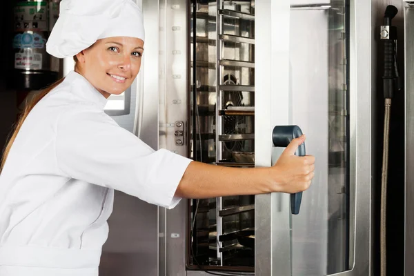 Female Chef Opening Oven Door