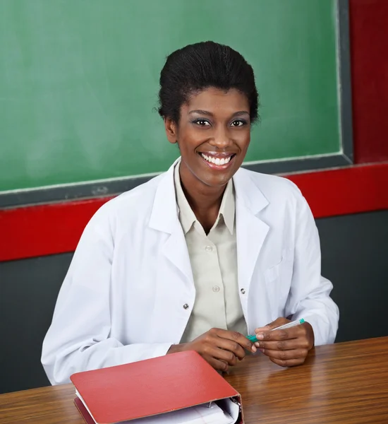 Confident Female Professor Sitting At Desk