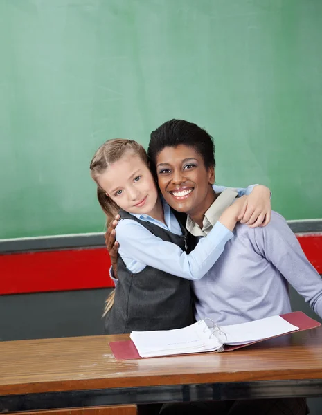 Schoolgirl Hugging Professor At Desk