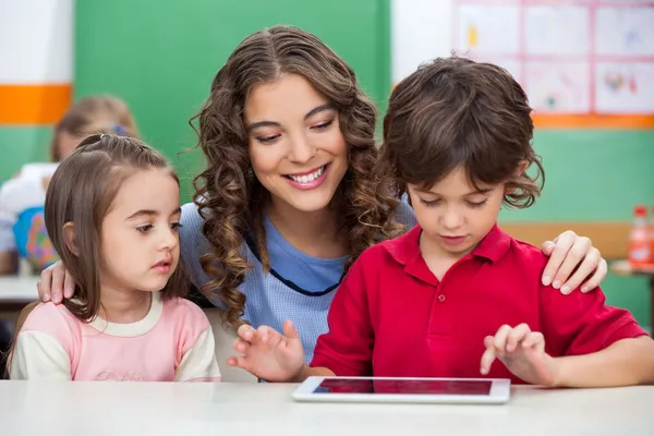 Children Using Digital Tablet With Teacher