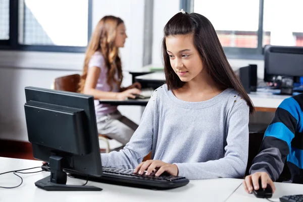 Girl Using Computer With Friends In Classroom