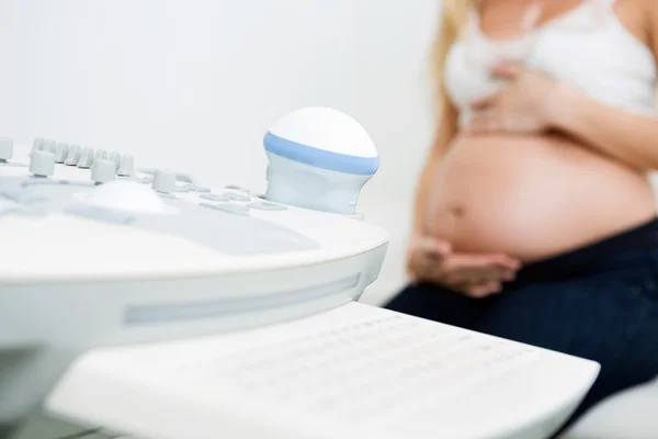 Ultrasound Machine With Pregnant Woman In Background