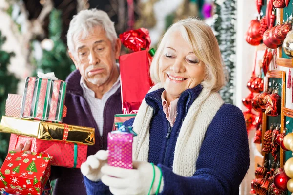 Woman Shopping With Tired Man Holding Presents In Store