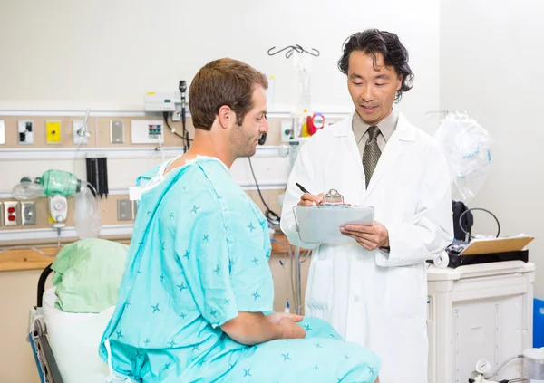 Doctor Discussing Medical Report With Patient In Hospital