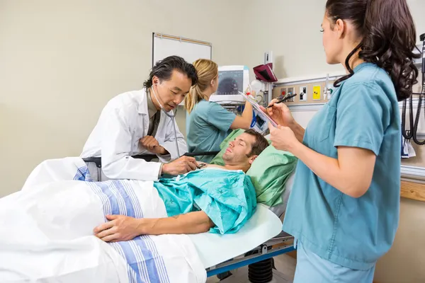 Doctor And Nurses Examining Patient In Hospital