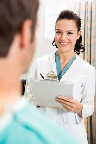 Female Doctor With Clipboard Looking At Patient