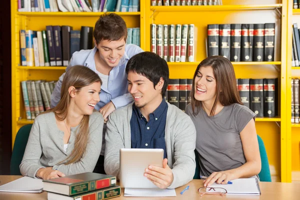 College Friends With Digital Tablet Studying In Library