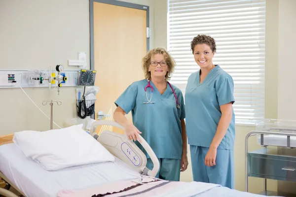 Nurses Standing Together By Bed In Hospital Room