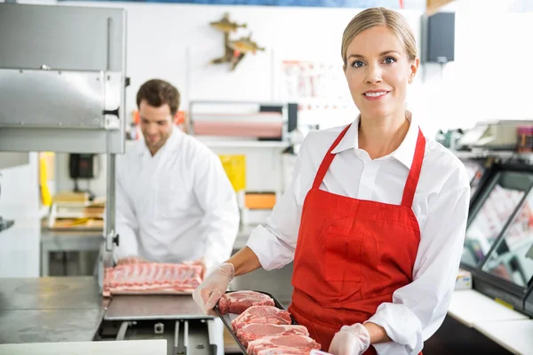 Smiling Butcher Holding Meat Tray At Store