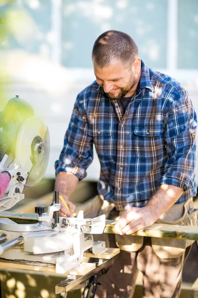 Happy Carpenter Marking On Wood At Table Saw