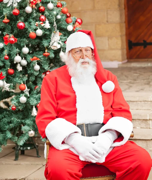 Man Dressed As Santa Claus Sitting In Front Of House