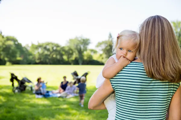 Mother Carrying Daughter Looking Away In Park