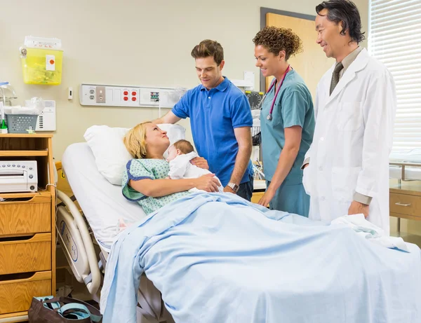 Medical Team And Man Looking At Mother With Babygirl