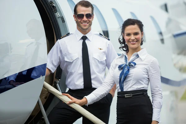 Happy Airhostess And Pilot Standing On Private Jet\'s Ladder