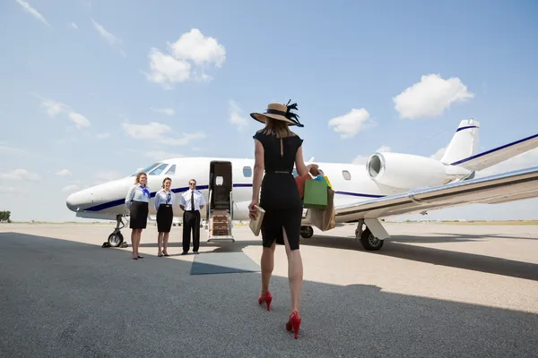 Woman Walking Towards Private Jet At Airport Terminal