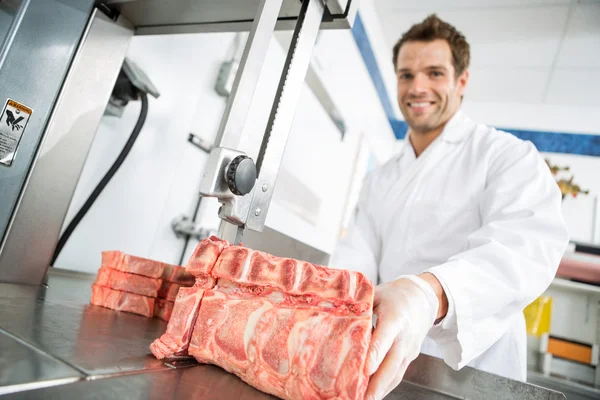Male Butcher Cutting Meat On Bandsaw