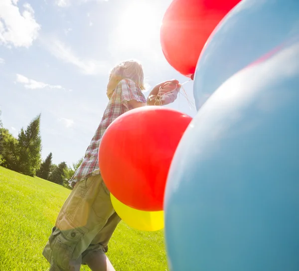 Boy With Balloons Walking In Green Meadow