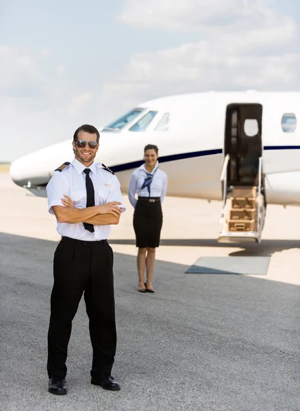 Full Length Pilot Against Stewardess And Private Jet At Terminal