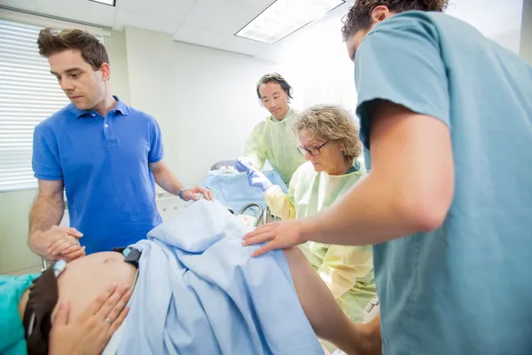 Medical Team Examining Pregnant Woman During Delivery In Operati